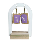 Pair of earrings with purple heart designs on a white stand.